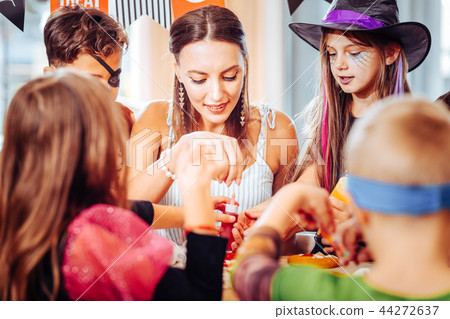 Dark-haired woman feeling happy while celebrating Halloween with children 44272637