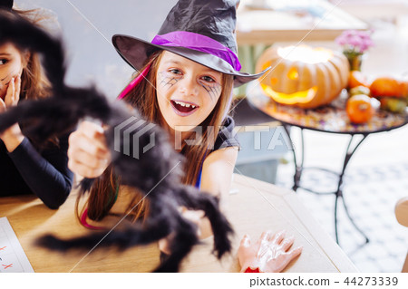 Beaming dark-haired girl with purple lips wearing wizard Halloween costume Beaming dark-haired girl with purple lips wearing wizard Halloween costume 44273339