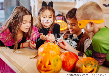 Four excited beaming children with painted faces wearing Halloween costumes Four excited beaming children with painted faces wearing Halloween costumes 44273524