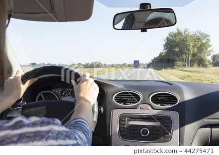 Close-up of the woman's hand holding the steering wheel. Girl driver rides behind the wheel of a car Close-up of the woman's hand holding the steering wheel. Girl driver rides behind the wheel of a car 44275471