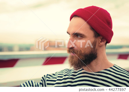Confident bearded man smiling while looking into the distance 44277897