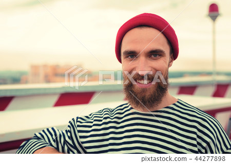 handsome man wearing striped clothes and red hat while standing and smiling handsome man wearing striped clothes and red hat while standing and smiling 44277898
