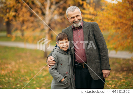 Grandpa and grandson spend time in autumn park. They hug each other and walk. Fmily time Grandpa and grandson spend time in autumn park. They hug each other and walk. Fmily time 44281262