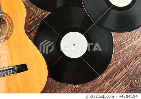 Vinyl records and guitar on wooden surface. 44284184