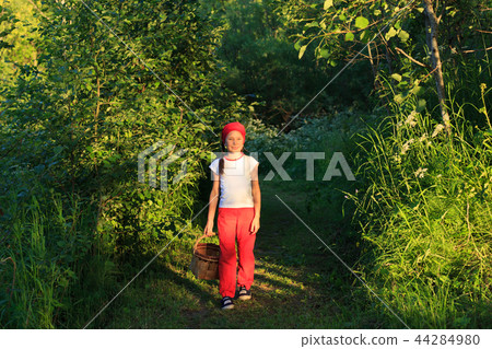 Young girl walking on a path through green woods carrying a basket Young girl walking on a path through green woods carrying a basket 44284980