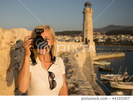 Traveler woman photographer with professional camera takes shot of Rethymno,Crete, Greece. 44285007