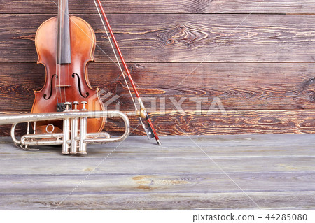 Aged violin and trumpet on wooden background. 44285080