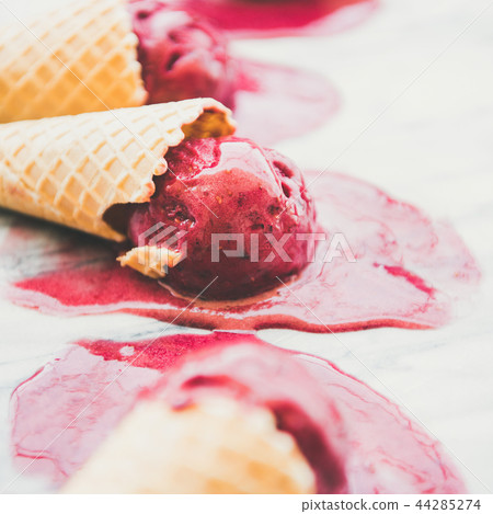 Raspberry sorbet ice-cream scoops in cones, selective focus, square crop 44285274