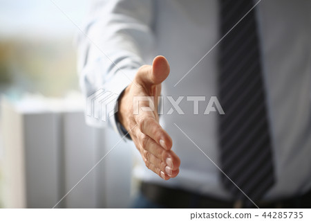 Man in suit and tie give hand as hello in office closeup 44285735