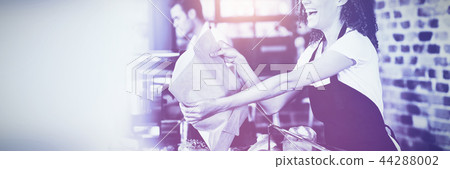 Smiling waitress giving paper bag to customer Smiling waitress giving paper bag to customer 44288002