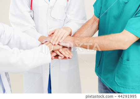 Doctor, surgeon and nurse join hands together. 44291995