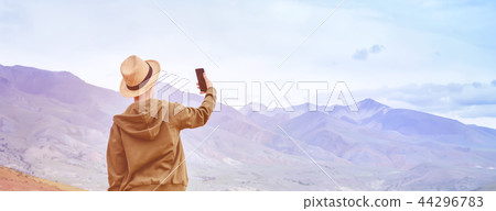 Girl tourist makes panorama of mountains on phone 44296783