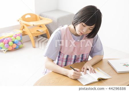 Nursery teacher writing childcare diary 44296886