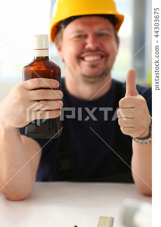 Arm of drunken worker in yellow helmet show OK 44303675