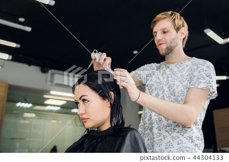 Hairdresser creating a hairstyle for beautiful woman closeup 44304133