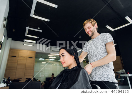 Professional hairdresser discussing female customer preferences in barbershop, choosing new hairdo 44304135