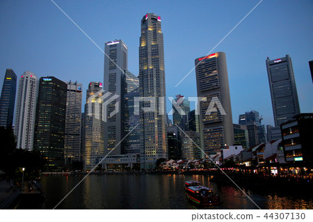 Night view of Singapore River with bam boats and skyscrapers rising behind it 44307130