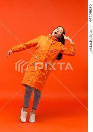 The young girl posing at studio in autumn jacket isolated on red 44309620