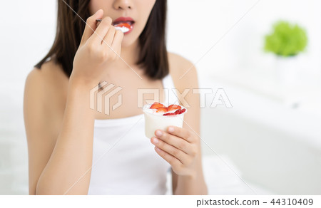 Closeup beautiful young Asian woman eating yogurt Closeup beautiful young Asian woman eating yogurt 44310409