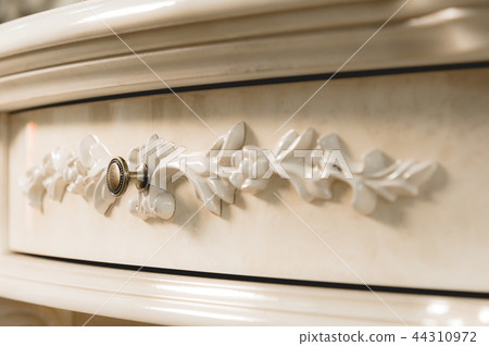 Close-up element of the drawer in the cabinet with a metal handle and wooden patterns. Detail of new 44310972