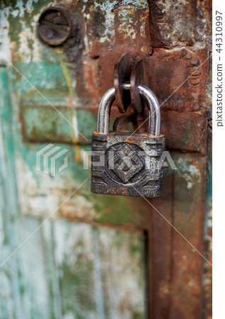 Old metallic padlock on wood,I have not painted the gate. Green shabby paint. Old metallic padlock on wood,I have not painted the gate. Green shabby paint. 44310997