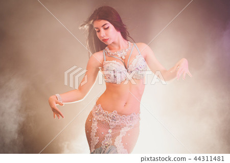adorable sexy traditional oriental belly dancer girl dancing on luminous smoke background. Woman in 44311481