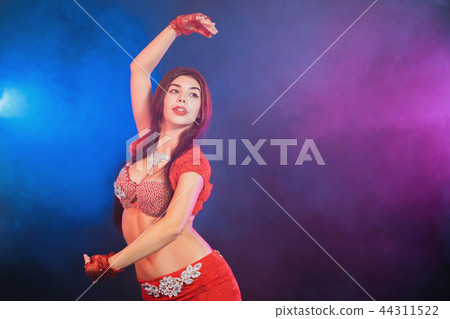 Woman in exotic shining red costume sexually moves her body. Sexy traditional oriental belly dancer 44311522