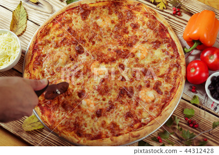Man cutting delicious seafood pizza. Man cutting delicious seafood pizza. 44312428