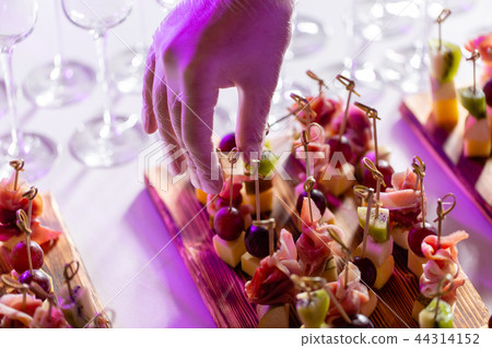 The waiter prepared and serves a snack. the buffet at the reception. Assortment of canapes on wooden The waiter prepared and serves a snack. the buffet at the reception. Assortment of canapes on wooden 44314152