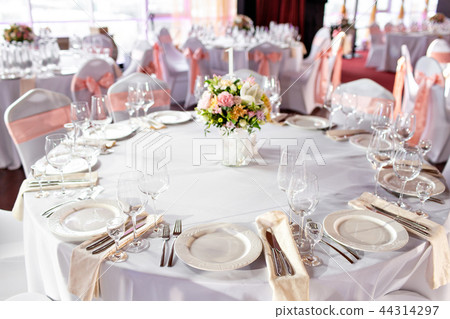 Round table at a luxury wedding reception. Beautiful flowers on the table. Serving dishes, glass Round table at a luxury wedding reception. Beautiful flowers on the table. Serving dishes, glass 44314297