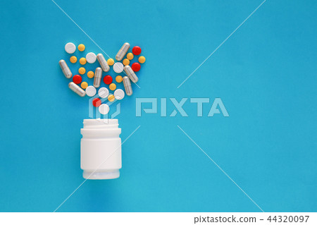 Pills heart out of pill bottle on blue background. Pills heart out of pill bottle on blue background. 44320097
