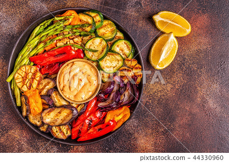 Grilled vegetables on a plate with sauce. Grilled vegetables on a plate with sauce. 44330960