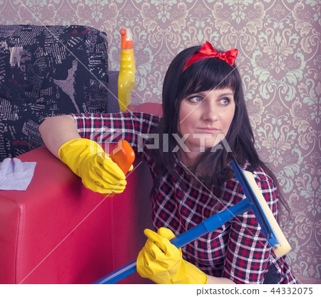 A girl in yellow gloves cleans the room and talks on the phone A girl in yellow gloves cleans the room and talks on the phone 44332075
