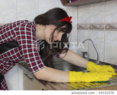 A girl in yellow gloves washes the kitchen sink 44332076