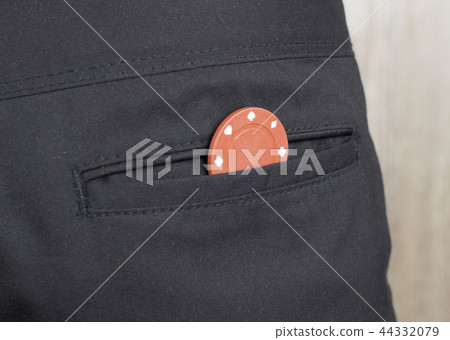 A chip from the casino in the back pocket of the pants, close-up 44332079