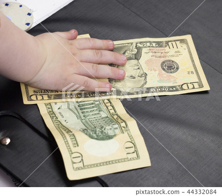 Child's hand holds money dollars on a black background, close-up, ten dollars Child's hand holds money dollars on a black background, close-up, ten dollars 44332084