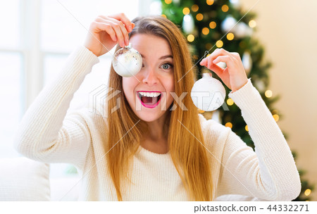 Happy woman holding Christmas ornaments in her house 44332271