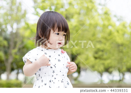 A little girl in a dress who dances against a fresh green tree. Fresh green, healthy, toddler, play, happiness image 44339331