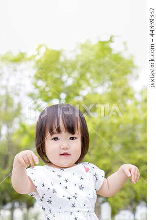 A little girl in a dress who dances against a fresh green tree. Fresh green, healthy, toddler, play, happiness image A little girl in a dress who dances against a fresh green tree. Fresh green, healthy, toddler, play, happiness image 44339332