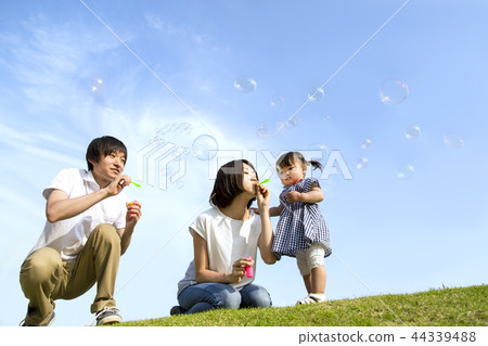 Happy parents and children playing with soap bubbles in the blue sky back at the park. Family, parent and child, happiness, love, childcare, health image Happy parents and children playing with soap bubbles in the blue sky back at the park. Family, parent and child, happiness, love, childcare, health image 44339488