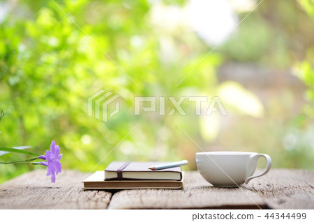 White cup and notebooks on wooden table White cup and notebooks on wooden table 44344499