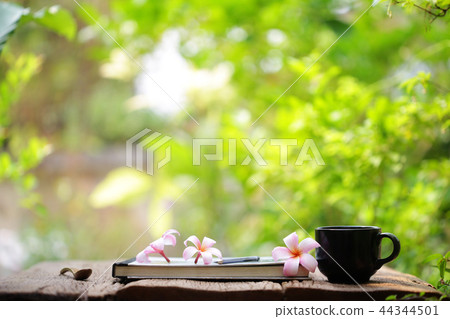 Black coffee cup and notebook on wooden table Black coffee cup and notebook on wooden table 44344501