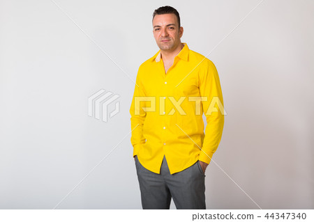 Portrait Of Man Wearing Yellow Shirt Against White Background 44347340