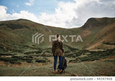 Young woman holding backpack and looking at the mountain Young woman holding backpack and looking at the mountain 44347408