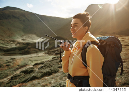 Confident hiker holding radio set and talking Confident hiker holding radio set and talking 44347535
