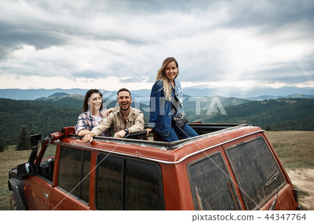 Joyful young friends travelling in the off road car 44347764