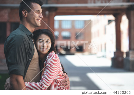 Happy man smiling while cuddling his positive girlfriend Happy man smiling while cuddling his positive girlfriend 44350265