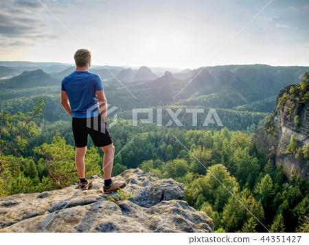 Man on stone observing landscape. Young sportsman 44351427