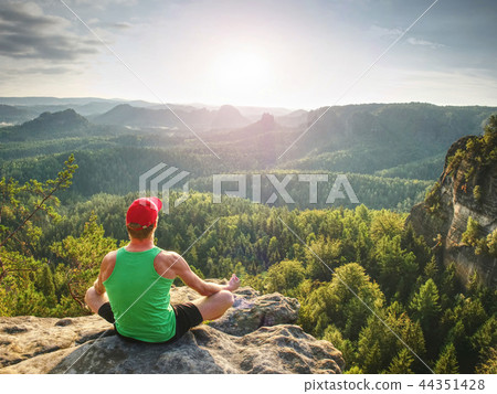Man meditates in yoga position in mountains above 44351428