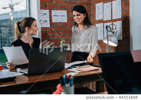 Young woman discussing plans with colleague in her office Young woman discussing plans with colleague in her office 44351688